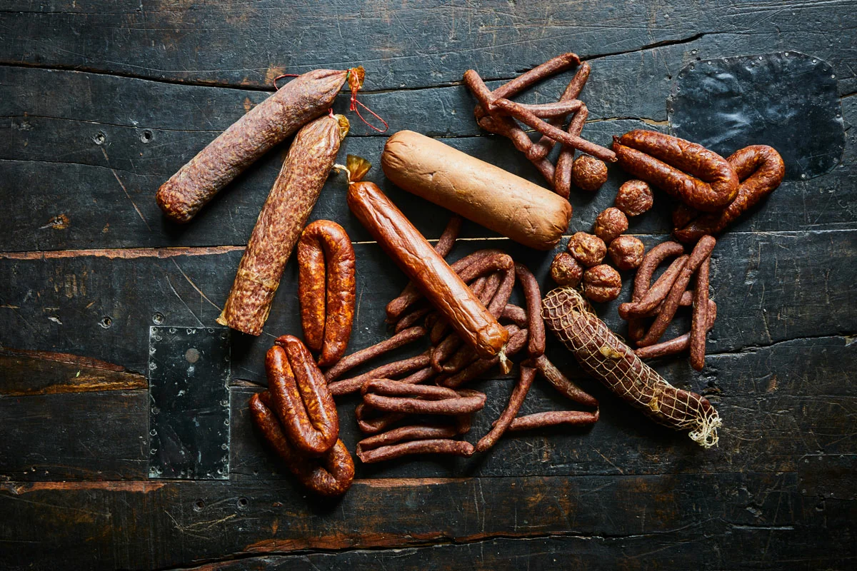 Różne rodzaje wędzonych kiełbas na ciemnym stole